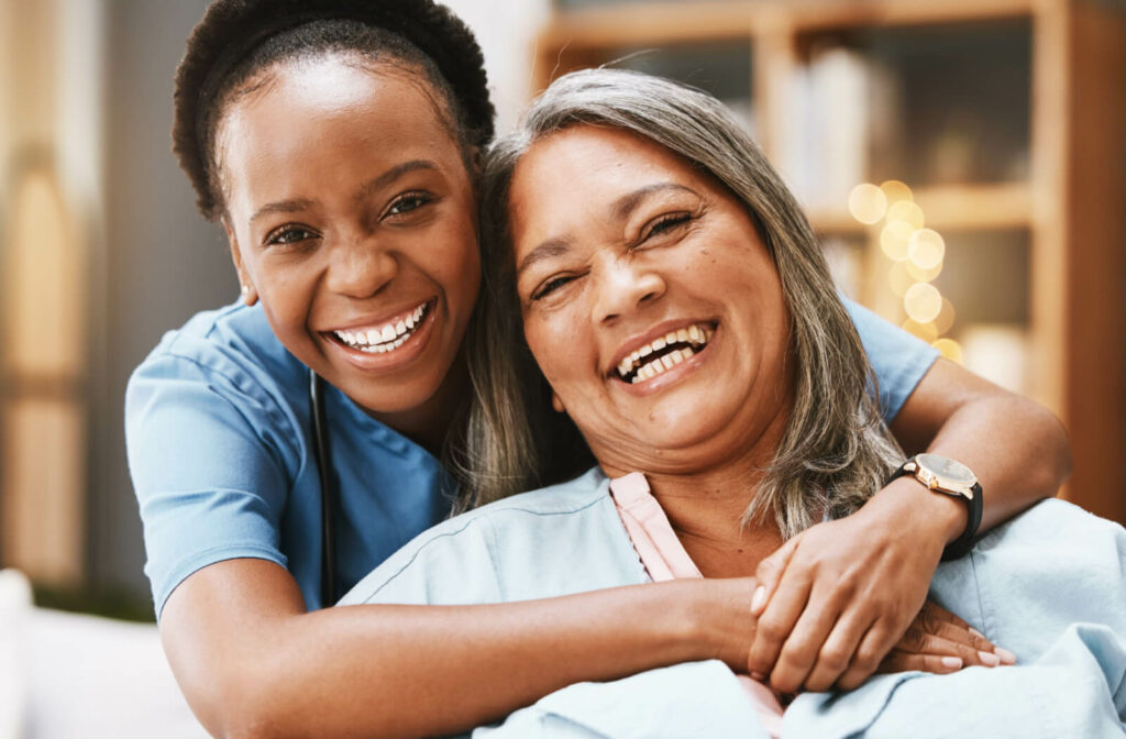 A short-term rehabilitation staff member and older adult hug and laugh together.