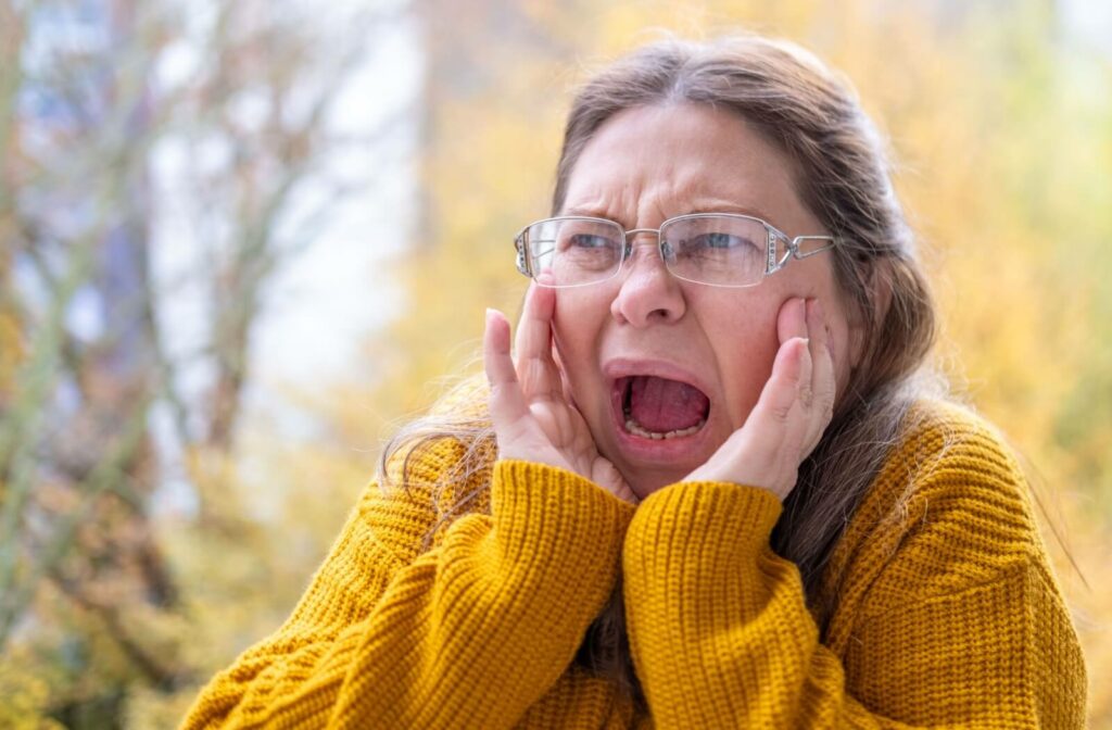 A person covers their ears with a pained expression, overwhelmed by sensory overload.
