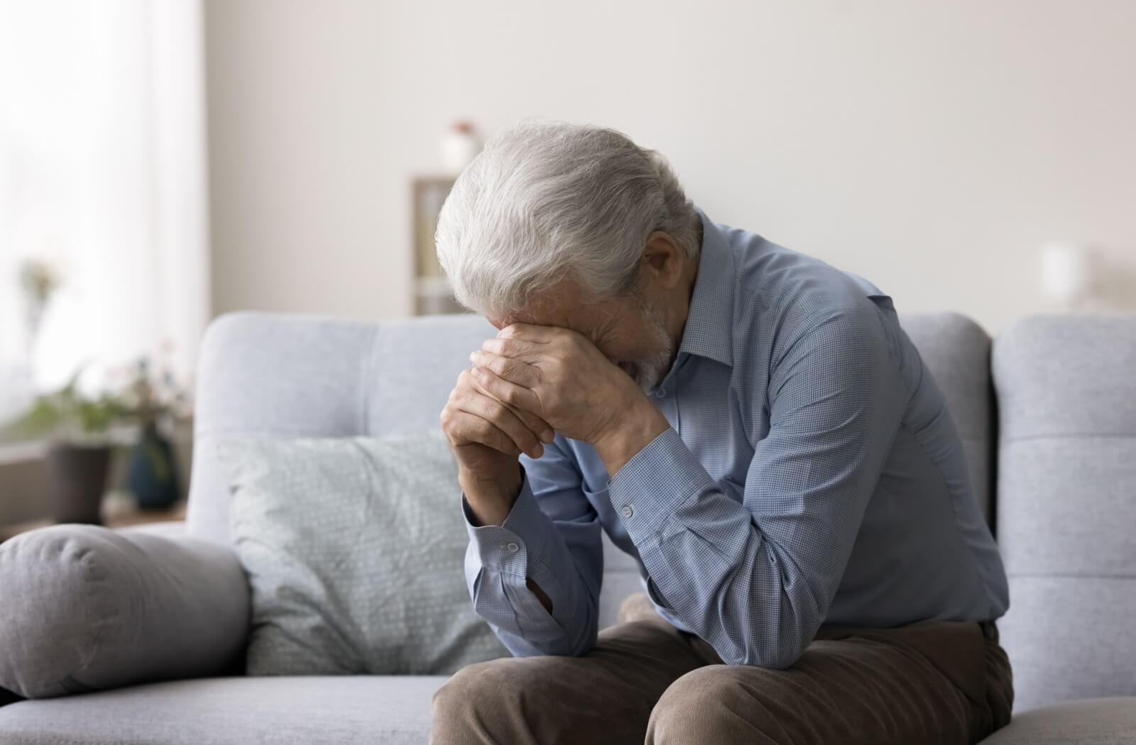 An older adult with anxiety resting their head in their hands in frustration