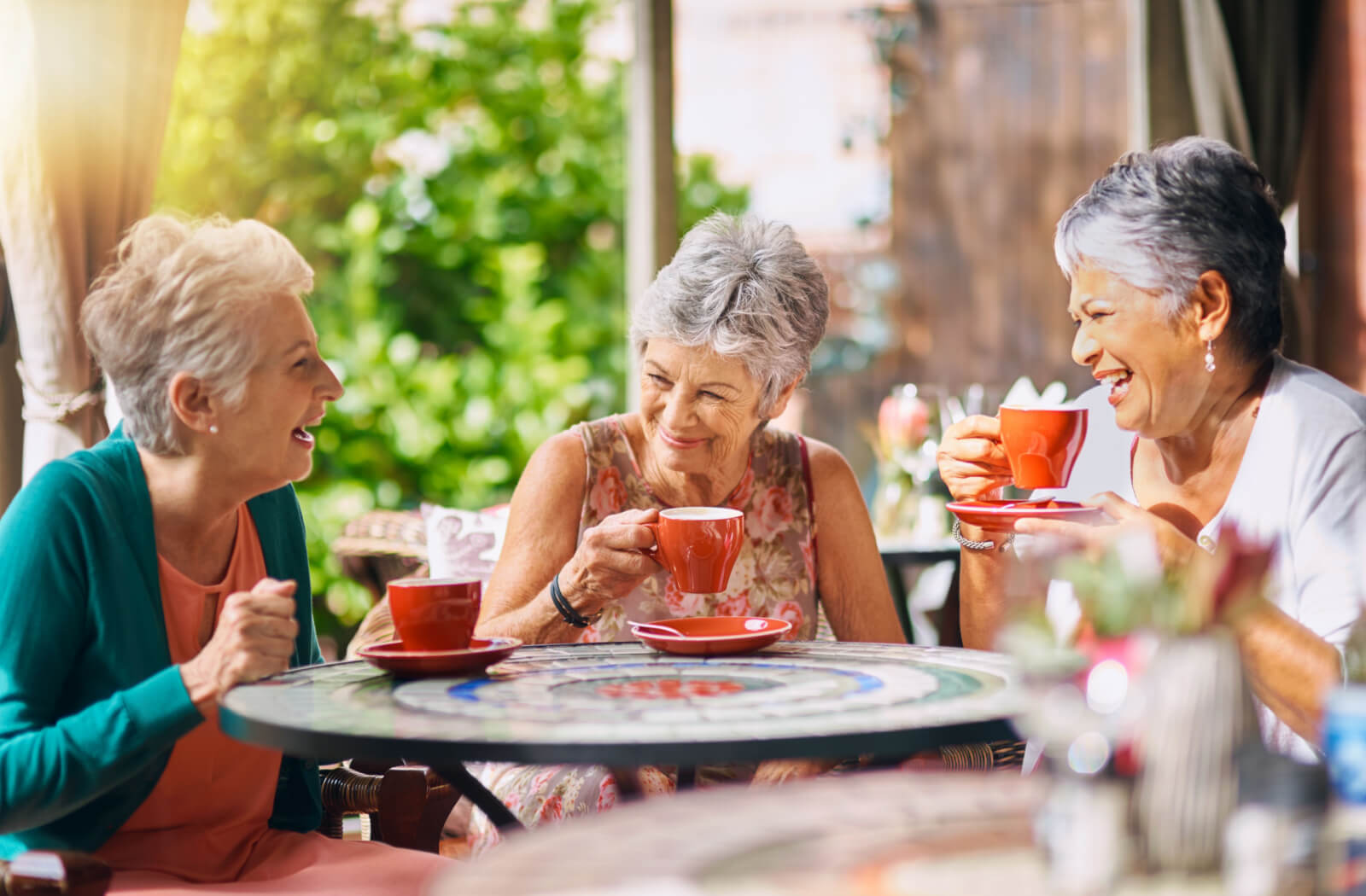 A group of senior woman having a conversation while enjoying a cup of coffee.